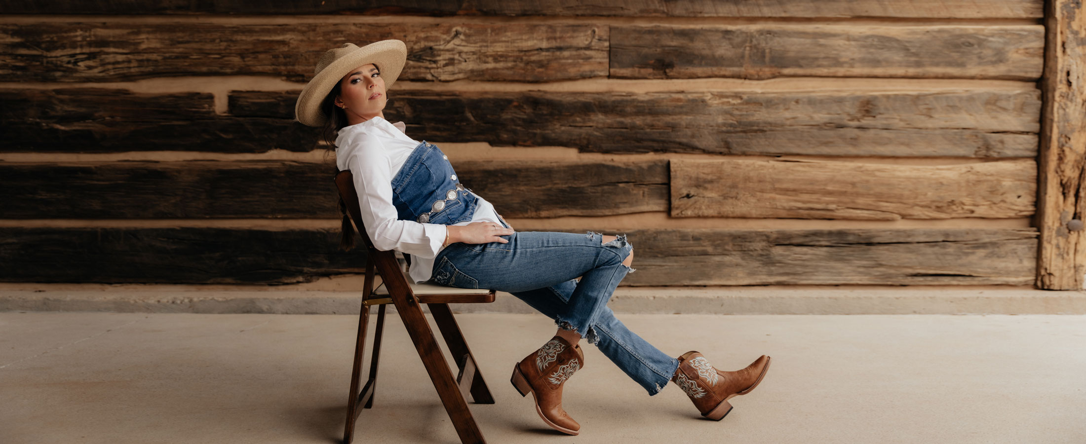 A woman sitting in a chair wearing Isabella 7" Western boot in brown